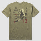 Back view of an olive green We Bred Death Tee featuring a graphic design with a bird perched on a bleeding knife, accompanied by text and symbols including "We Bred Death," "Mac V Soc," and the number 13.