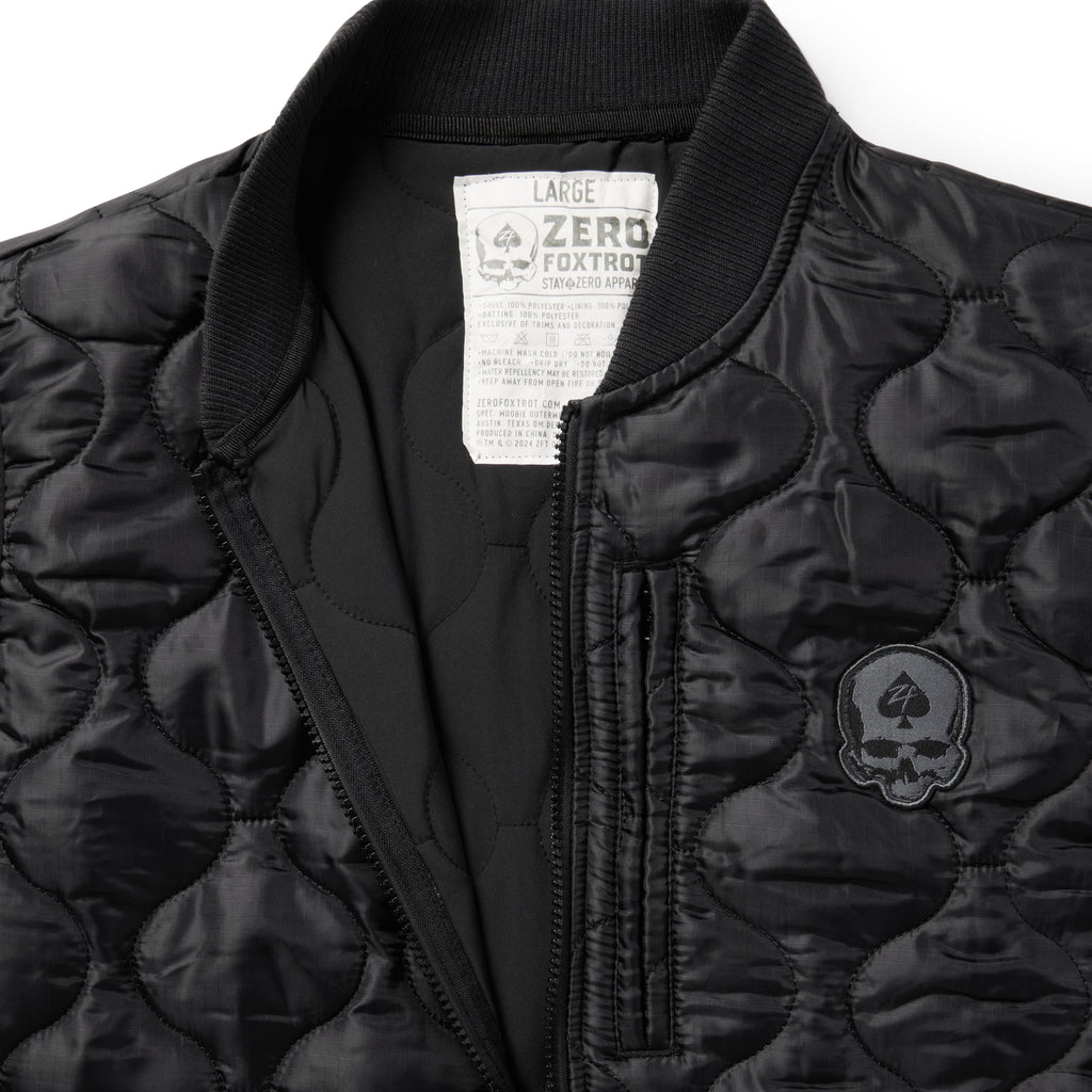 Woobie Vest (Last Chance), black quilted vest close-up with ribbed collar, front zipper, chest pocket, skull patch, and interior size label