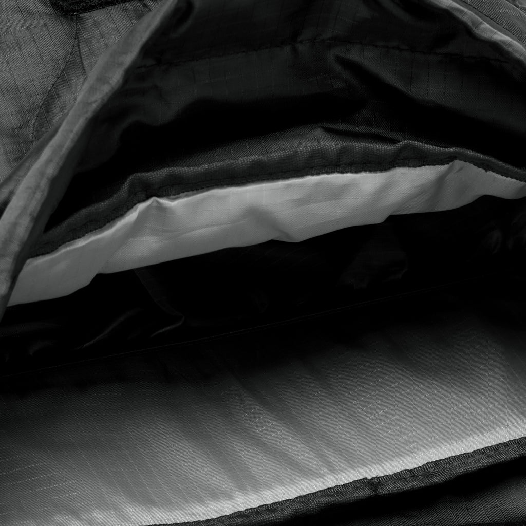Close-up view of the interior compartment of the Woobie Backpack showing a light-colored padded laptop sleeve and spacious storage area lined with durable fabric.