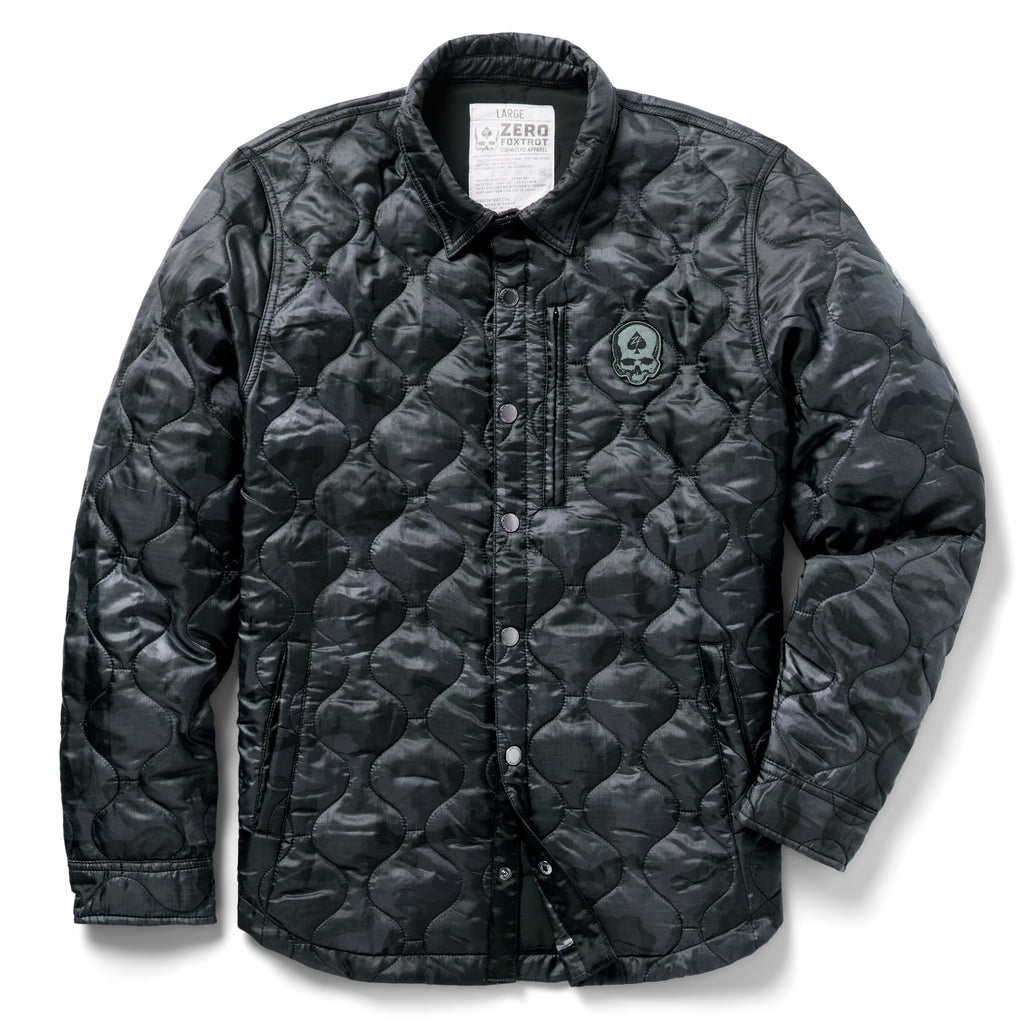 Woobie Shacket in black with quilted fabric, button front, collar, long sleeves, and a small skull patch on the chest against a white background