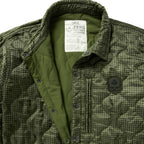 Woobie Shacket in olive green camouflage with quilted lining, corduroy collar, snap button front, chest pocket, and embroidered patch detail