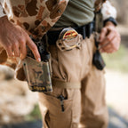 Tac Pants worn with a utility belt and camouflage gear in a close up outdoor scene with visible cargo pockets and tactical accessories