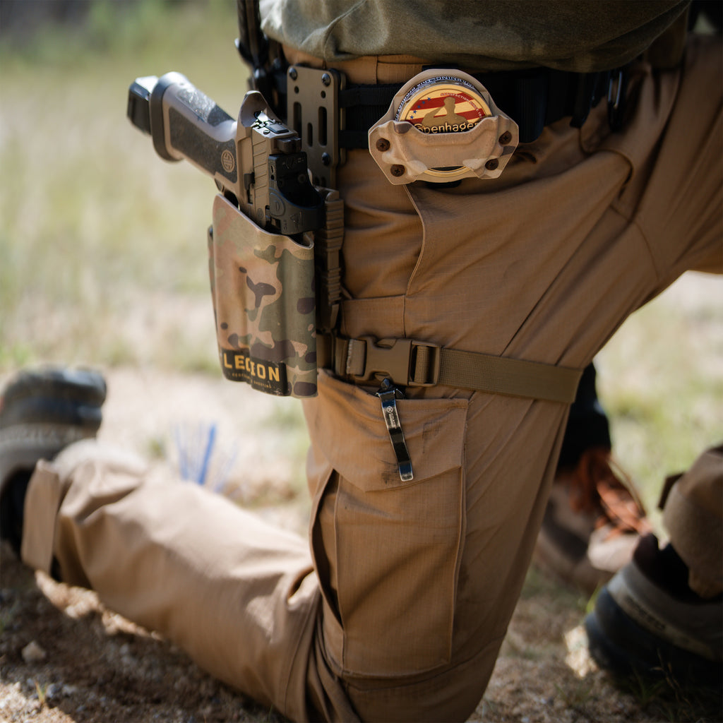 Tac Pants in tan worn while kneeling outdoors with a tactical belt holster utility pouch and large thigh pocket visible