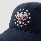 Close-up of a navy blue ZF Old Glory Cap featuring an embroidered white eagle surrounded by stars and a red banner with the text "Zero Foxtrot" and the numbers "1776" below.