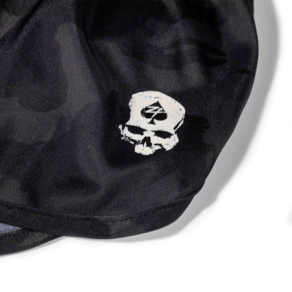 Close-up of black fabric with a white skull wearing a cap featuring a spade symbol, printed on ZF Silkies - Camos shorts.