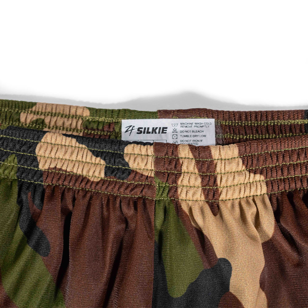 Close-up of the waistband and fabric pattern of ZF Silkies - Camos, featuring woodland camouflage colors including green, brown, tan, and black with an elastic waistband and care label.
