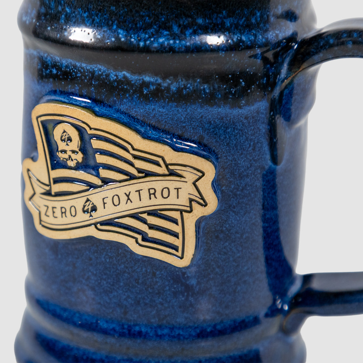 Close-up of a blue ceramic USA Flag Stein with a detailed emblem featuring a flag and the text "Zero Foxtrot" on its side.