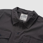 Close-up of a charcoal CPO Shirt showing the collar, button-front closure, and two chest pockets with buttons on a soft textured fabric.