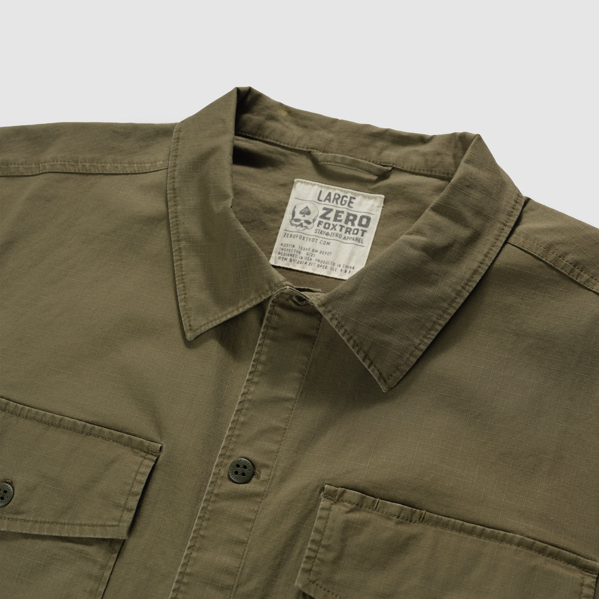 Close-up view of an olive green CPO Shirt showing the collar, front buttons, and chest pockets on a flat surface.