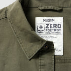 Close-up of a dark olive Chore Jacket collar and label showing medium size, made from cotton blend fabric with durable stitching details.