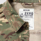 Close-up of a medium-sized Chore Jacket in camouflage fabric showing the collar and the inner label with the Zero Foxtrot brand logo and garment details.