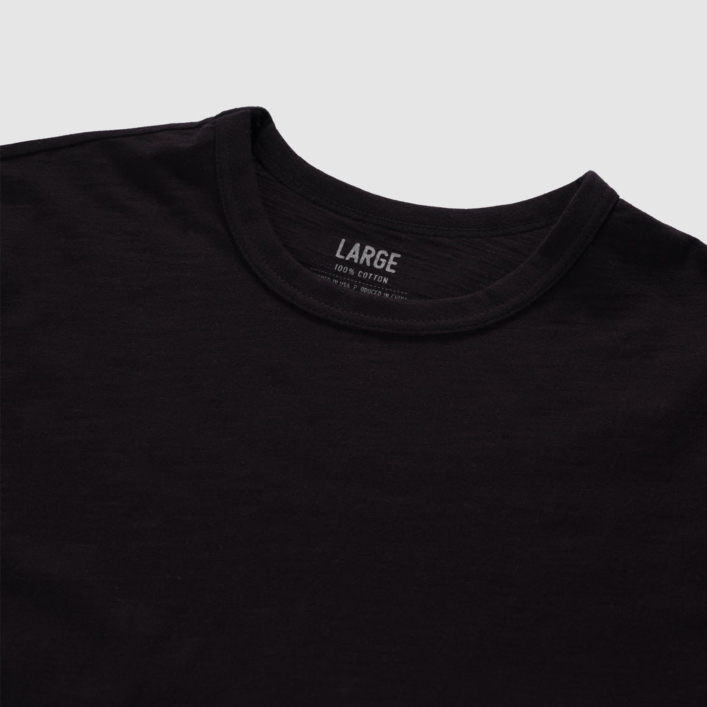 Black cotton skivvy tee with a classic round neckline, soft texture, and subtle slub fabric detail, shown in a large size.