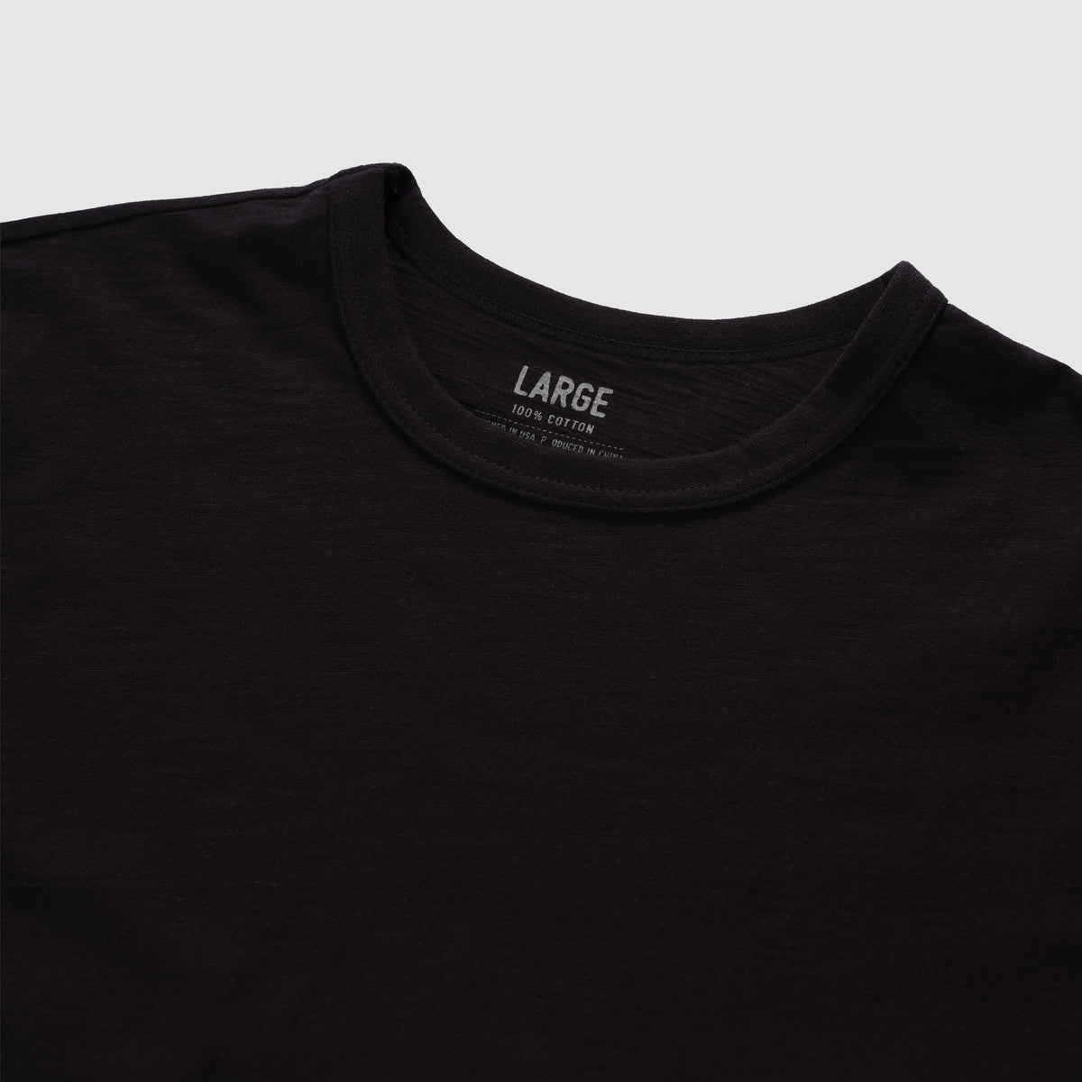 Black cotton skivvy tee with a classic round neckline, soft texture, and subtle slub fabric detail, shown in a large size.