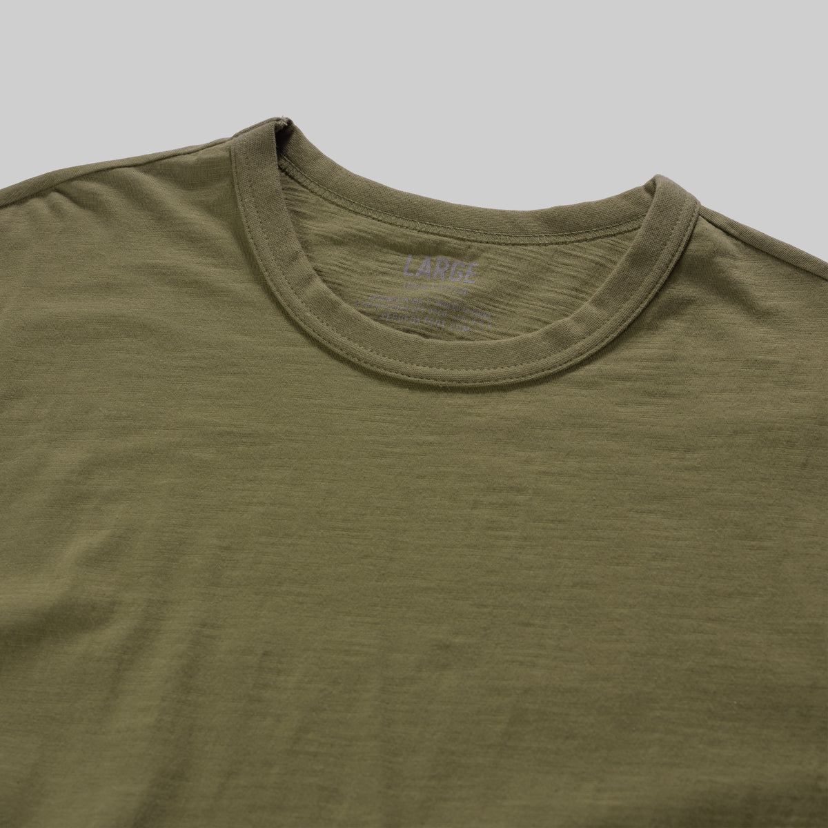 Close-up of an olive green Cotton Skivvy Tee with a crew neckline, showing soft, lightweight fabric and fine stitching details.