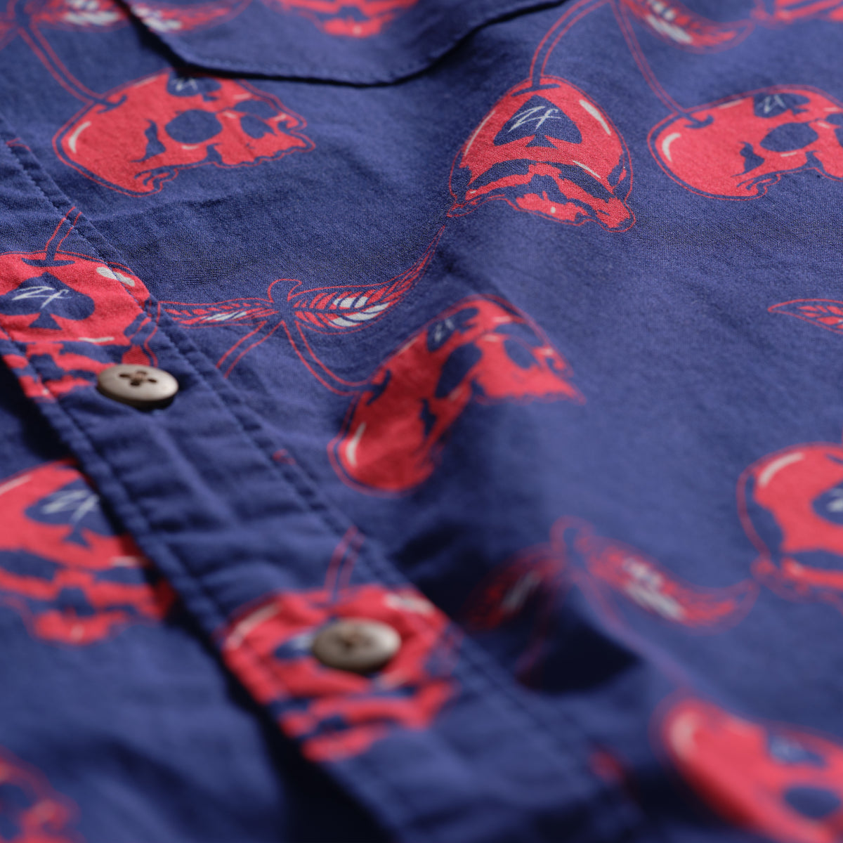 Surf Shirts (Last Chance), close-up of a navy blue button-up shirt with a red crab print, front placket, and brown buttons