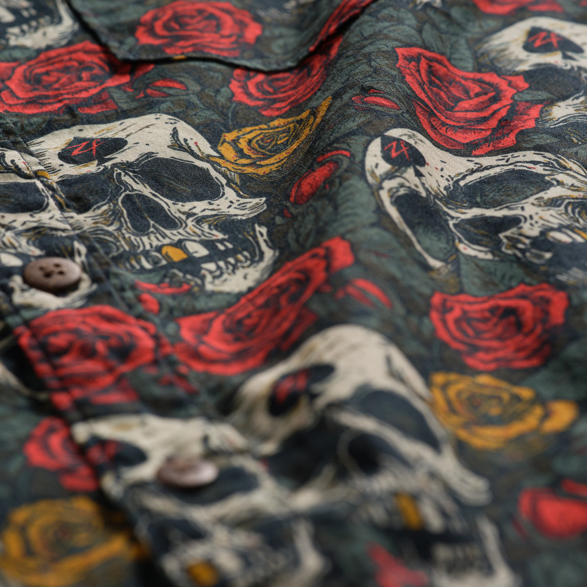 Surf Shirts (Last Chance) with dark fabric patterned with skulls, red roses, and gold accents, showing textured material and buttons