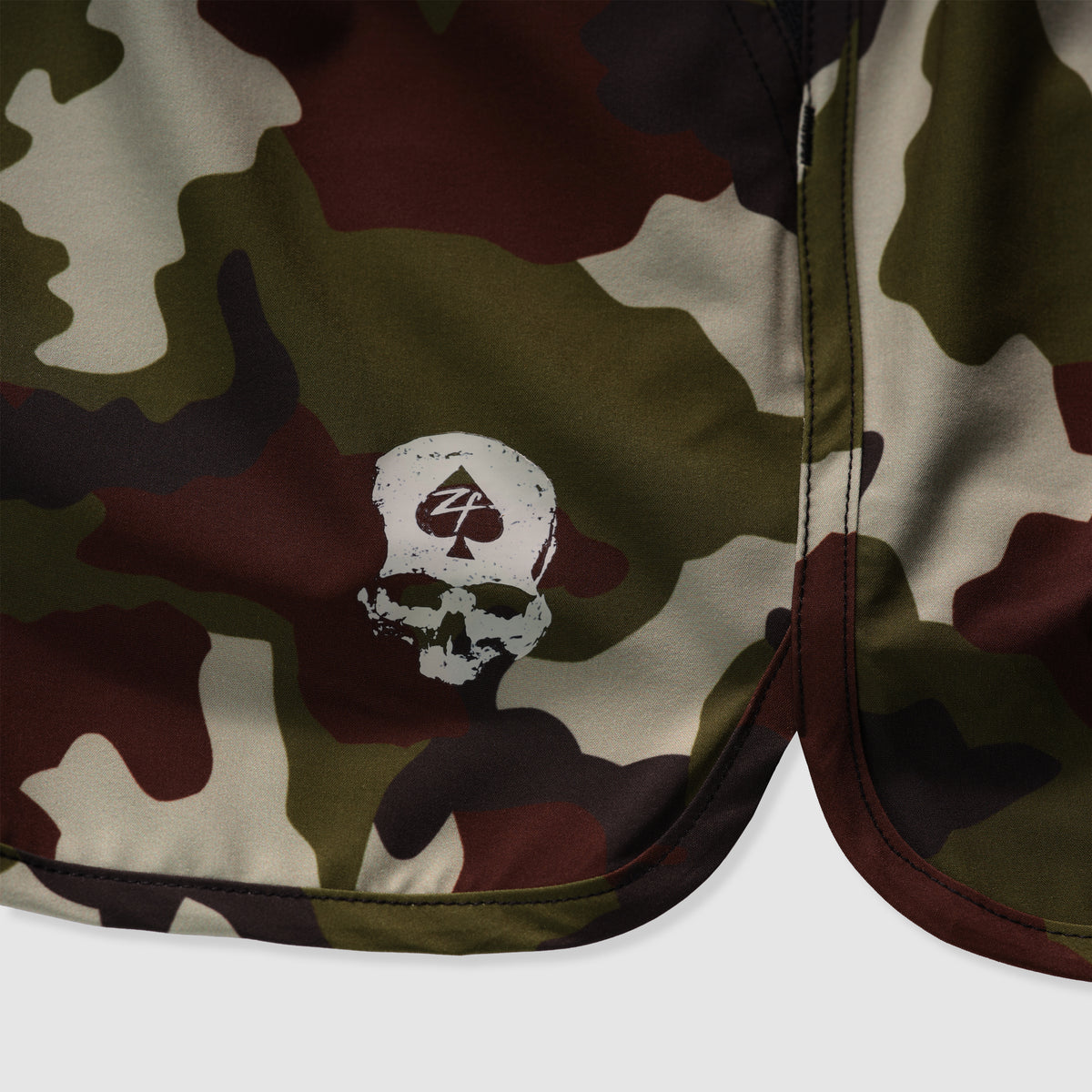 Close-up of camouflage patterned fabric with a white skull and spade logo detail on the edge of the Zero Shorts - 7" Inseam.