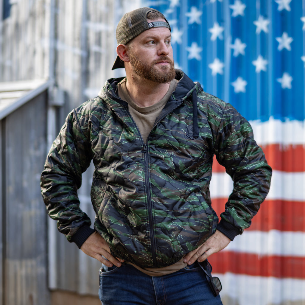 Woobie Zip Hoodie worn by a bearded man in camouflage with a front zipper and hood standing against an American flag backdrop
