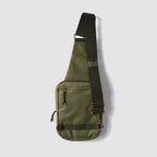 Surplus EDC Sling in olive green with adjustable black shoulder strap, front zip pocket, and metal hardware against a light background