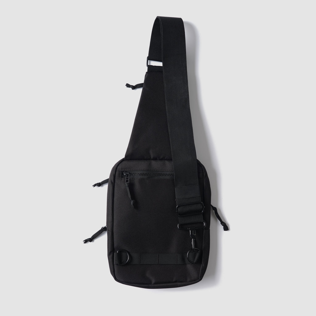 Surplus EDC Sling black crossbody bag with adjustable shoulder strap front zip pocket and compact rectangular design against a light background