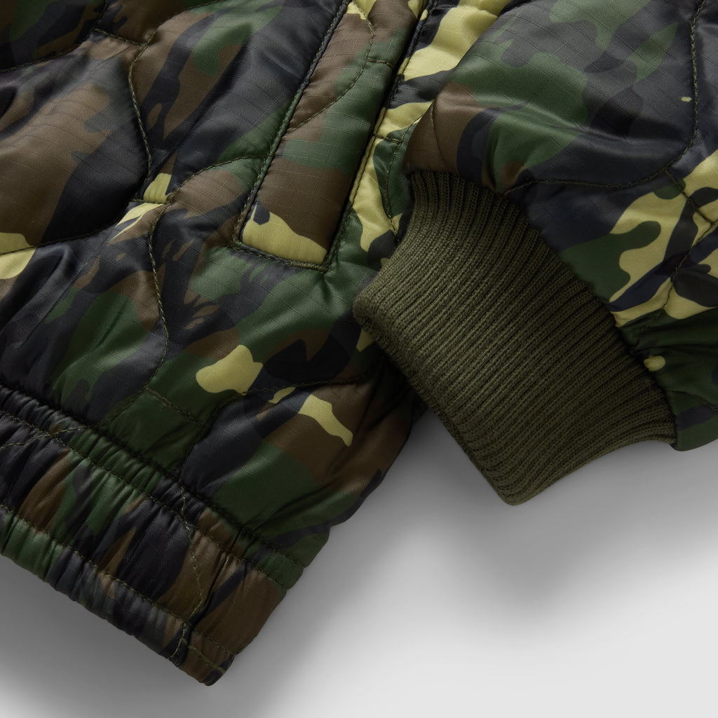 Woobie Zip Hoodie close up showing quilted camouflage fabric, black zipper detail, and ribbed olive green sleeve cuff