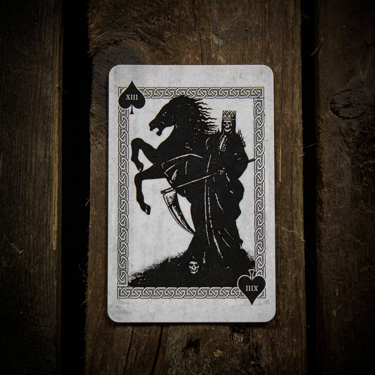 The Horseman death card featuring a crowned rider on a rearing black horse, framed by ornate Celtic knotwork and displayed on a rustic wooden surface