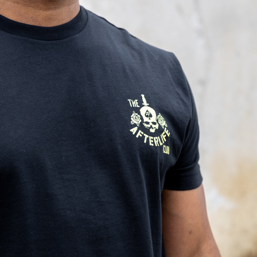 Apple a Day Tee in black with a small cream skull graphic and lettering on the left chest, shown on a model.